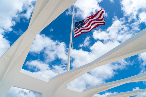Pearl Harbor, Hawaii, USA - April 7, 2021: American Flag flying at half staff at the USS Arizona Memorial in Pearl Harbor in Oahu Hawaii.