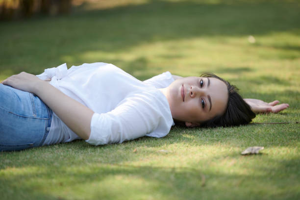 Beautiful smiling young woman lying on ground in park an looking at camera