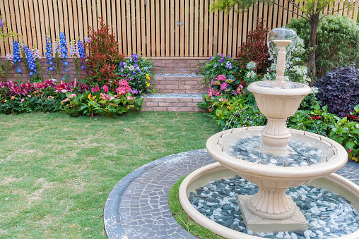 Fountain and wooden fence of backyard flower garden