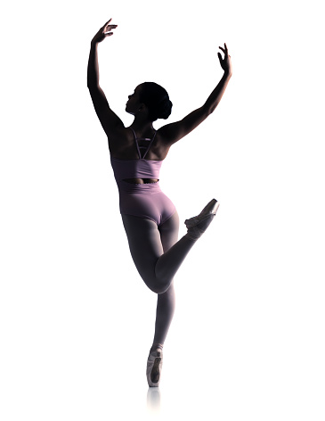 Ballerina in Pink Chiffon Dress jumping Split. Ballet Dancer in Silk Gown Pointe Shoes. Graceful Woman in Tutu Skirt dancing over Gray Studio Background