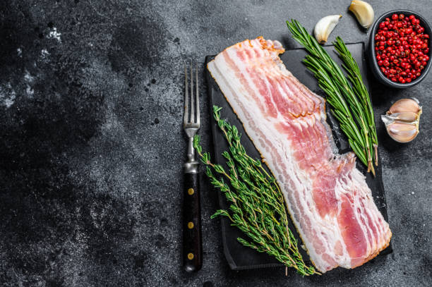 istock Raw sliced pork bacon ready for cooking. Black background. Top view. Copy space 1312226796