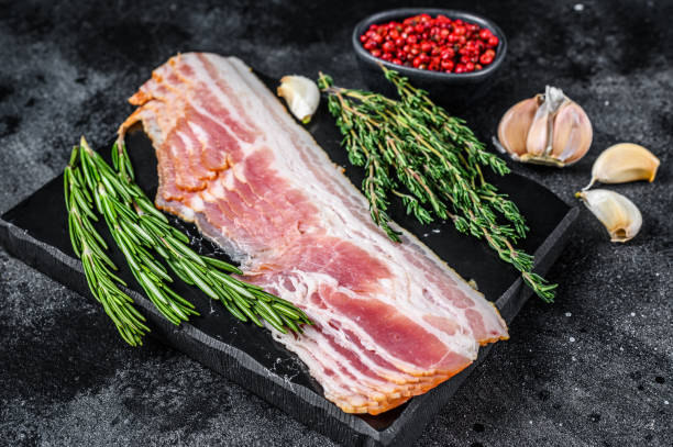 istock Raw sliced pork bacon ready for cooking. Black background. Top view 1312226803
