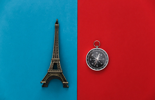 Compass and eiffel tower figurine on red-blue background. Travel, adventure flat lay. Top view