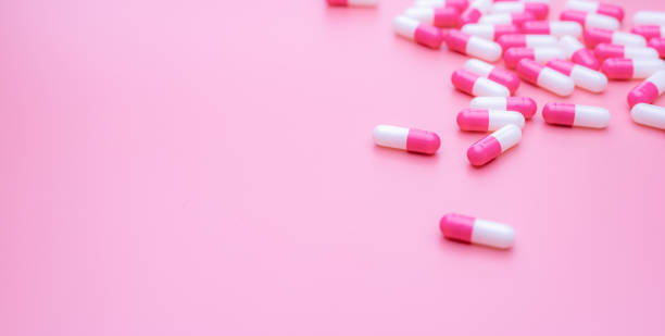 Pink-white antibiotic capsules pill spread on pink background. Antibiotic drug resistance concept. Antibiotic drug smart use. Antimicrobial drug. Health budget and policy. Pharmaceutical industry. píldora de cápsulas antibióticas de color blanco rosada se propaga sobre fondo rosado. concepto de resistencia a los antibióticos. uso inteligente de antibióticos. fármaco antimicrobiano. presupuesto y política de salud. industria farmacéutica.