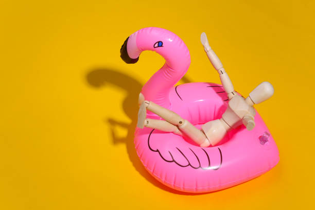istock Puppet mannequin with inflatable flamingo on yellow bright background. Beach vacation concept. Summer rest. Minimalism 1312233204