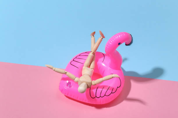 istock Puppet mannequin with inflatable flamingo on pink blue bright background. Beach vacation concept. Summer rest. Minimalism 1312233215