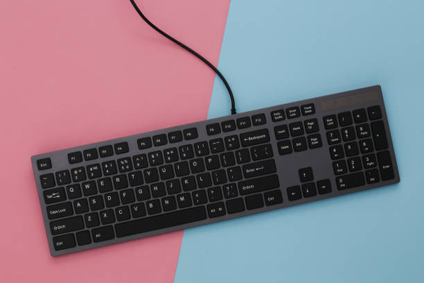 istock PC keyboard on pink blue background. Top view 1312234580