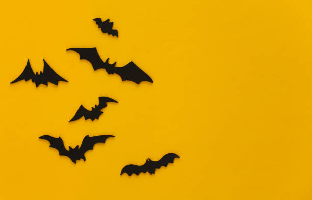 istock Halloween background, decorations and scary concept. Black bats fly over yellow background, Copy space 1312236042