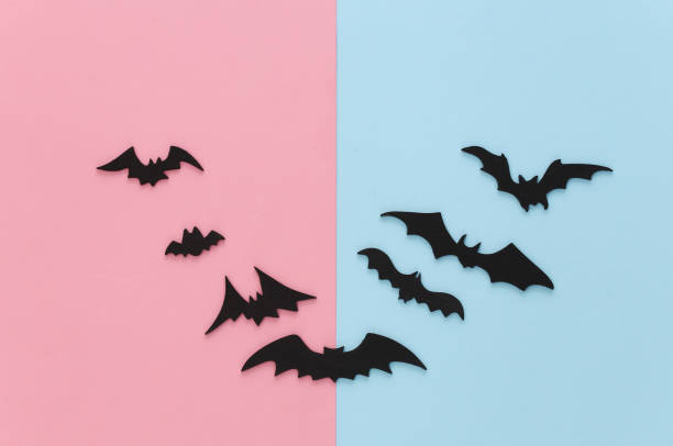 istock Halloween background, decorations and scary concept. Black bats fly on pink blue background 1312236695