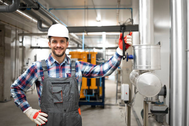 retrato do engenheiro de fábrica segurando o braço na válvula e de pé pelo sistema de aquecimento ou resfriamento da sala da caldeira. manutenção de instalação de gás. - heating engineer - fotografias e filmes do acervo