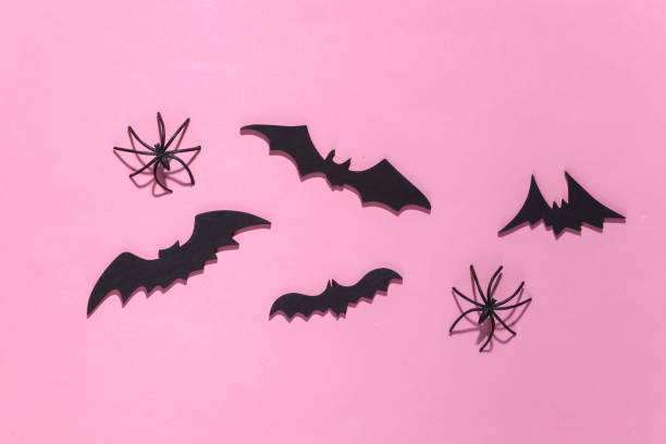 istock Halloween background, decorations and scary concept. Spiders and black bats fly over pink bright background. Top view 1312238066