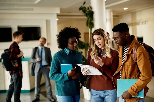istock Multi-ethnic group of college students reading from a book in a hallway. 1312241373