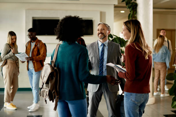 istock Happy mature teacher and students communicating at university hallway. 1312241422
