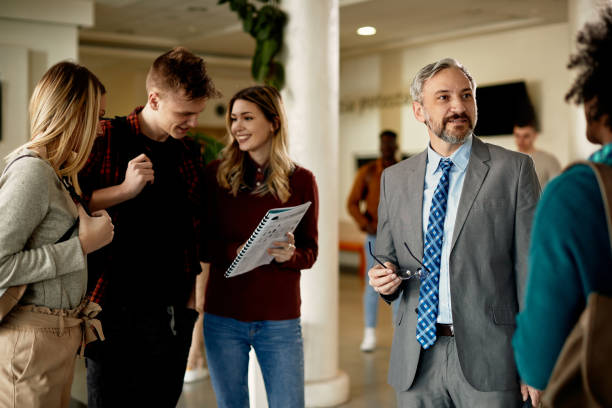 istock Mature university professor talking to his students in a hallway. 1312241503