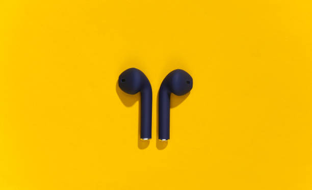 istock Classic blue color true wireless bluetooth headphones or earbuds on bright yellow background. Top view 1312241573