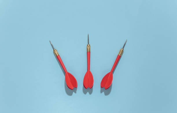istock Three red plastic darts with metal tip on blue bright background with deep shadow. Top view. Flat lay 1312241679