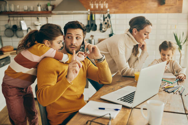 istock Little girl distracting her father who is making phone call while working at home. 1312241725