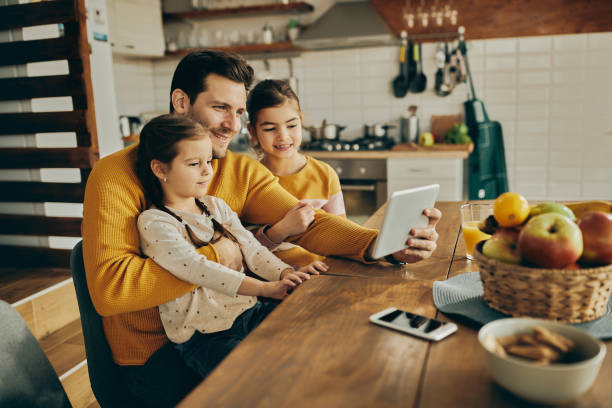 istock Happy father and his daughters using digital tablet while relaxing at home. 1312241780
