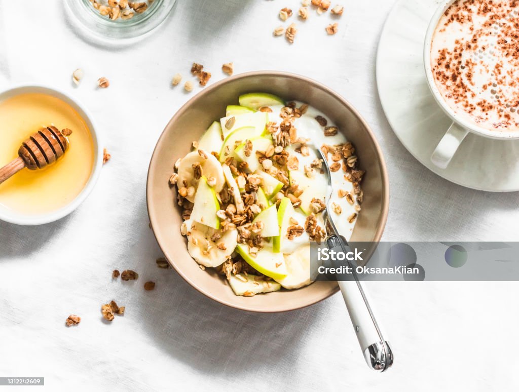 Greek yogurt with granola, banana, apple, honey on a light background, top view. Delicious breakfast Yogurt Stock Photo