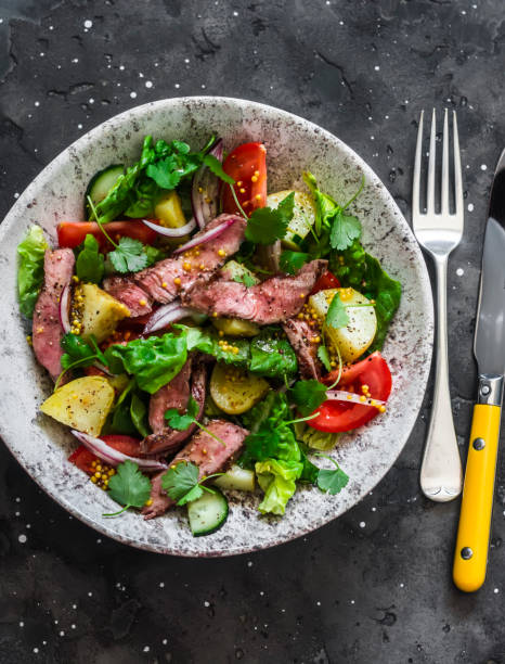 istock Potato, beef steak, romano and vegetable salad on a dark background, top view. Balanced diets healthy food 1312243094