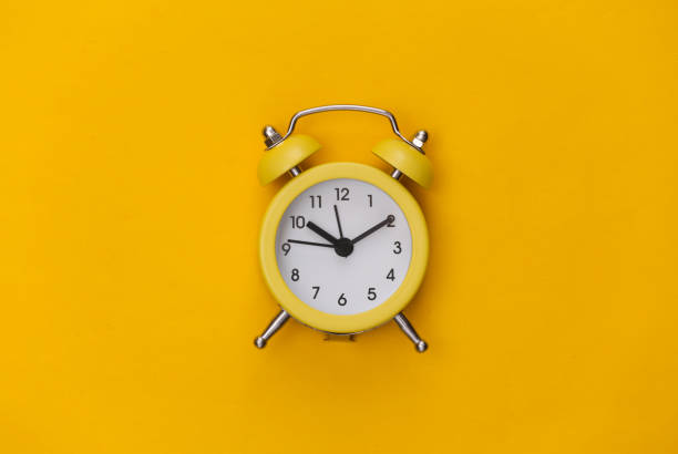 istock Yellow retro alarm clock on a yellow background. Top view. Minimalism 1312243642