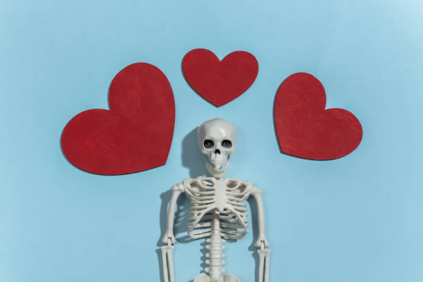 istock Skeleton and red decorative hearts on a bright blue background. Valentine's day or halloween theme. Top view. Flat lay 1312243742