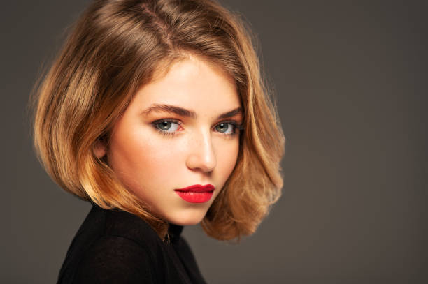 verticale de plan rapproché d’une jeune fille adulte avec le cheveu moyen de longueur.  photo d’un modèle de mode posant au studio. jolie jeune femme avec les lèvres rouges regardant l’appareil-photo. portrait de beauté. - cheveux mi longs photos et images de collection