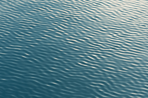 Small waves abstract or rippled water texture background, lake, sea or river with sunset or sunrise reflection, water surface