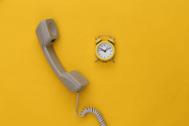 istock Telephone receiver and alarm clock on a yellow background. Top view 1312245088
