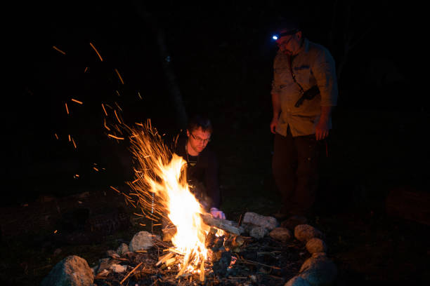 istock Camping men around a camp fire at night 1312245218