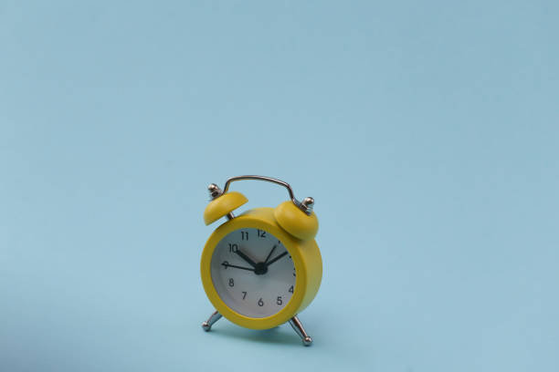 istock Yellow retro alarm clock on blue background. 1312245425