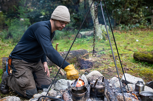 Traditional camp cooking in a pot over hot coals of a fire pit.
