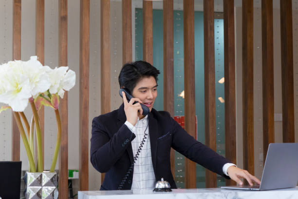 Receptionist is service customer at counter. Receptionist is service customer at counter. He is using phone. hotel reception hotel service technology stock pictures, royalty-free photos & images