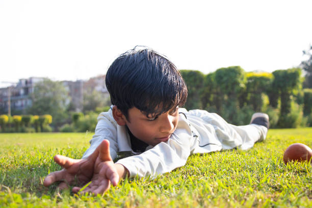 istock a boy fielding on the ground during cricket game 1312248991