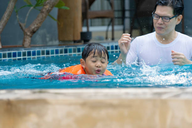 istock Father and son play at swimming pool. 1312250643