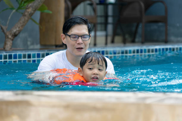 istock Father and son play at swimming pool. 1312250655