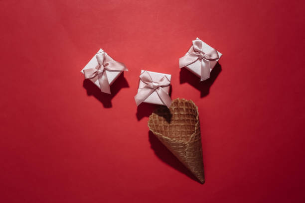 istock Ice cream waffle cone with gift boxes on red bright background. Top view 1312251508