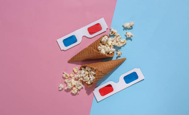 istock Ice cream waffle cones with popcorn, 3d glasses on pink and blue bright pastel background with deep shadow, top view. Movie time. Flat lay minimal composition 1312251909