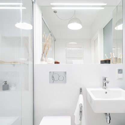 Small and stylish bathroom in white with shower, big mirror, classic washbasin and decorative ceiling light