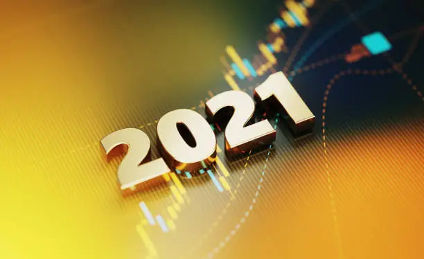 Gold colored 2021 sitting on yellow financial graph background. Horizontal composition with selective focus and copy space. Investment, stock market data and finance concept.