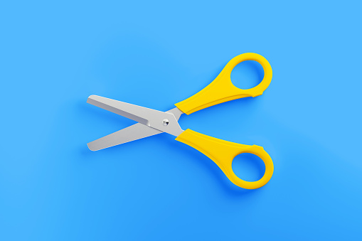 Yellow scissor sitting over blue background. Horizontal composition with copy space.