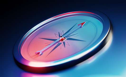 Compass sitting over dark blue metallic background. Horizontal composition with copy space.