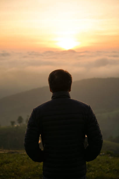 istock man watching sunrise alone at hilltop 1312259569