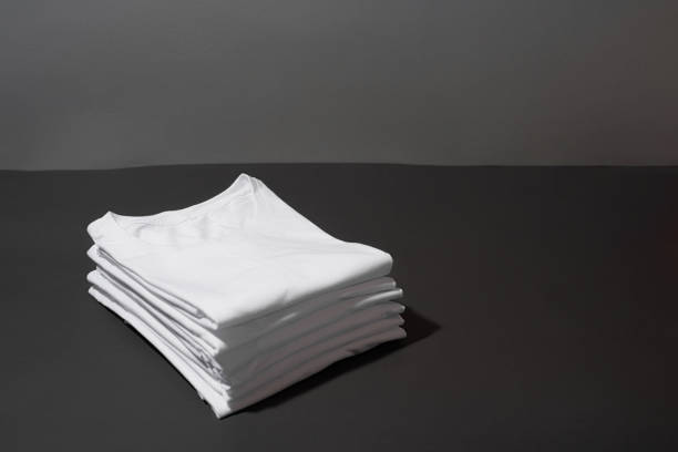 istock Stack of folded white cotton t shirts isolated over dark gray background 1312259794