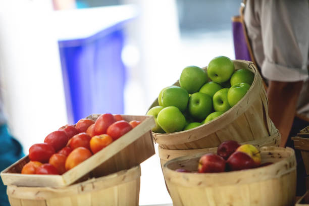 Apples and tomatoes in baskets at green market, copy space