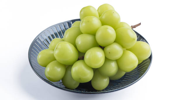 白い背景に分離された青いプレートにシャインマスカットグリーンブドウの美しい束。 - grape white grape green muscat grape ストックフォトと画像