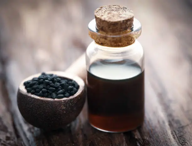 Nigella seeds and essential oil in a glass bottle