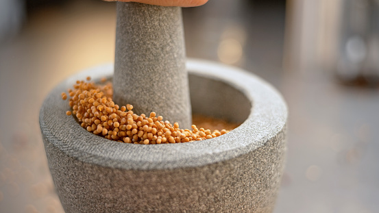 Close-up of mustard seeds in mortar and pestle.