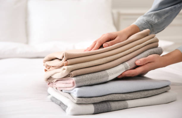 istock Woman with folded cashmere clothes on bed, closeup 1312265024