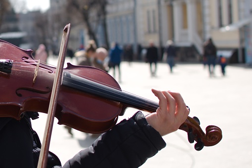 Ukraine Zhytomyr March 26, 2021. hands of street musician on violin on blurred background of pedestrian street